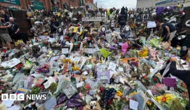 Hundreds of flowers and tributes to Ozzy Osbourne lie on the bench and floor on Black Sabbath Bridge.