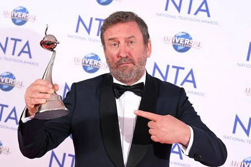 Lee Mack holds up an award
