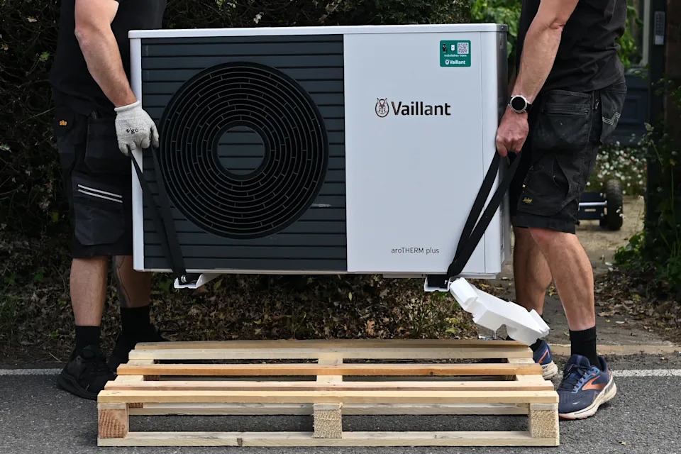 Heat pump installers Simon Mockler (L) and Richard Wilkins (R), from Lotus Energy, carry a Vaillant aroTHERM plus heat pump into a residential property for installation in Farnham, Surrey, southwest of London, on June 2, 2025. (Photo by Justin TALLIS / AFP) (Photo by JUSTIN TALLIS/AFP via Getty Images)          