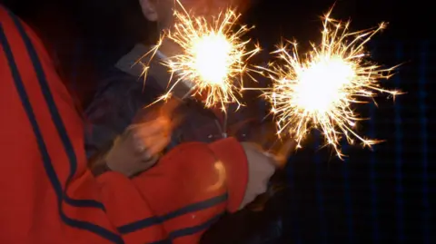 PA Media Children holding sparklers - their faces cannot be seen
