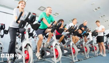 A group of people riding exercise bikes in a gym.