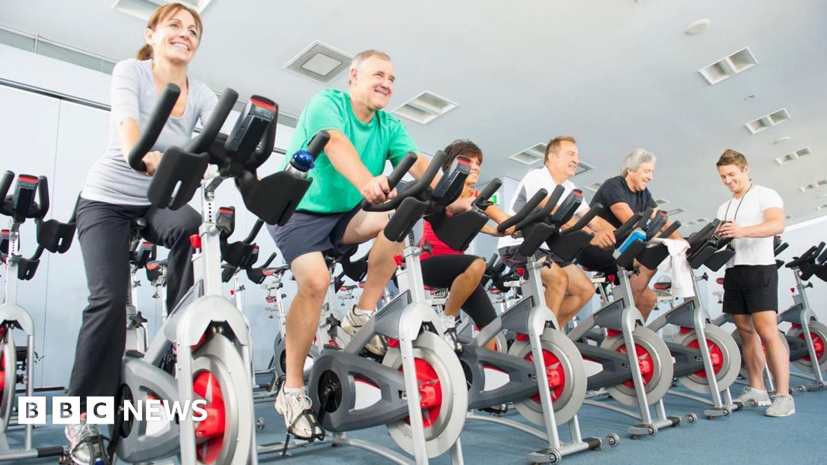A group of people riding exercise bikes in a gym.