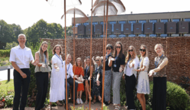 A group of people stood in a row in the garden smiling with their arms stretched out