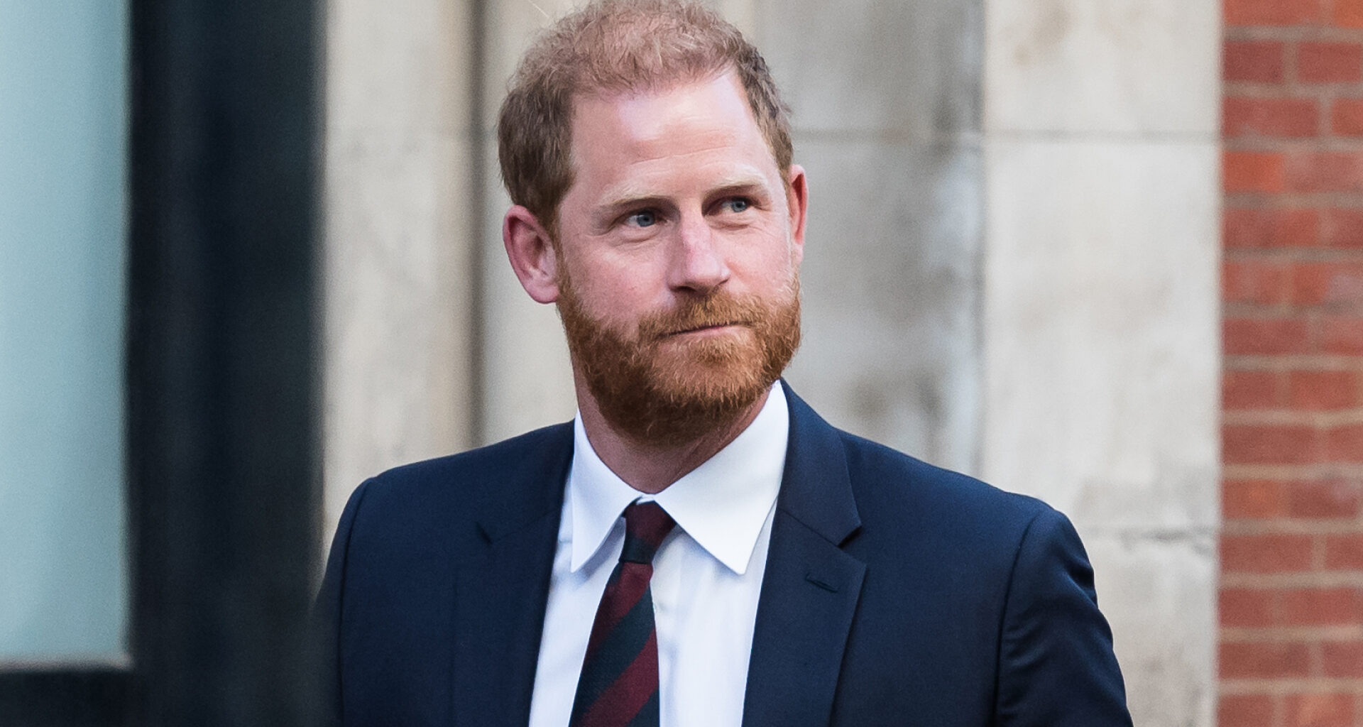 Prince Harry wearing a blue suit and red and blue striped tie