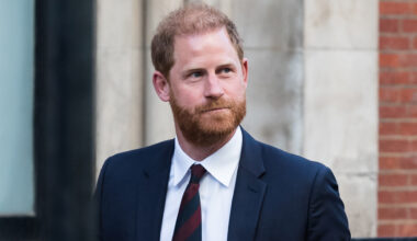 Prince Harry wearing a blue suit and red and blue striped tie