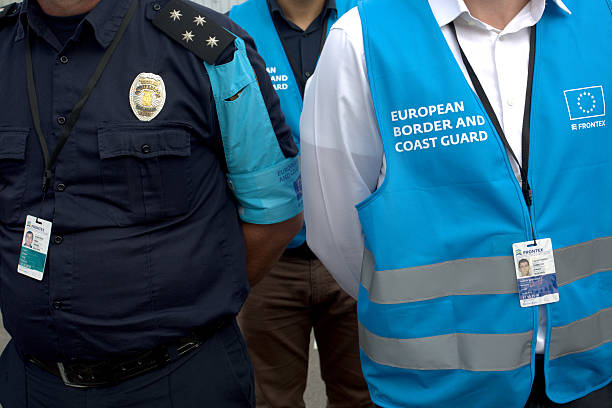 European Border and Coast Guard officers standing side by side in uniform and blue vests.