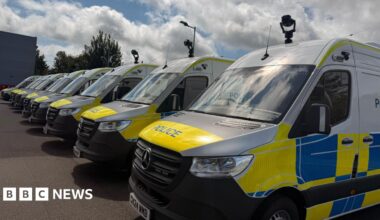 Nine police vans lined up with cameras attached to the top