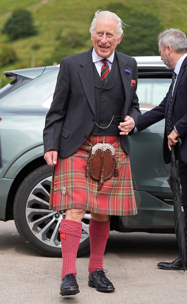 King Charles in a kilt smiling widely