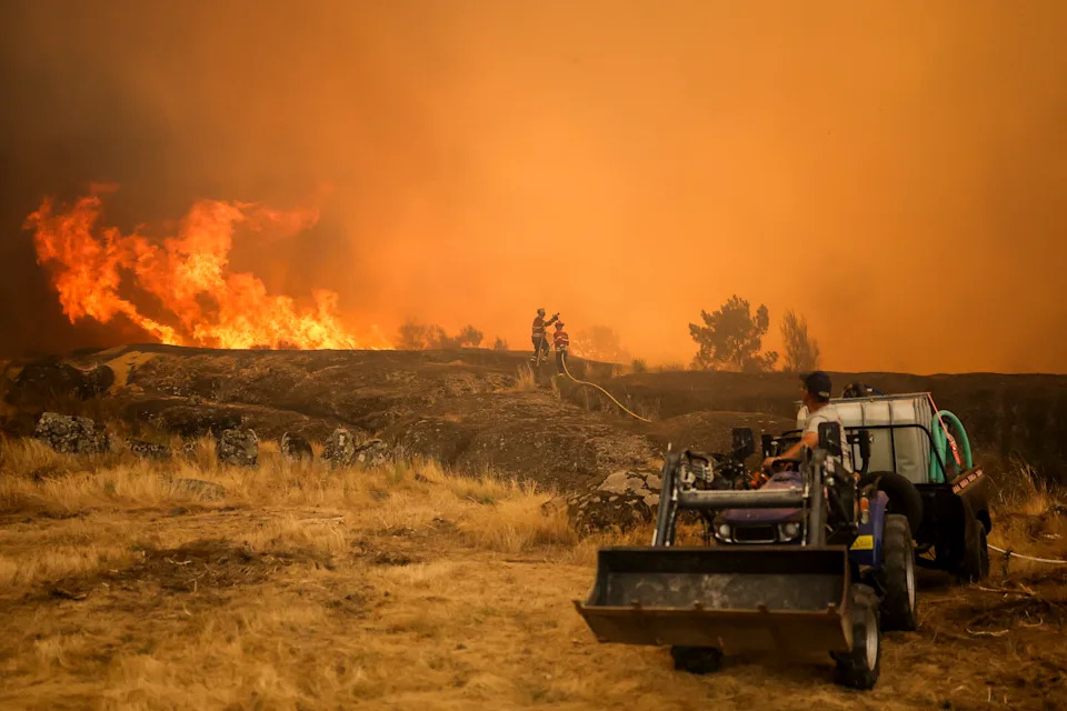 Firefighters and residents work to extinguish a wildfire at Casal do Monte village in Trancoso, on August 13, 2025. (Photo by PATRICIA DE MELO MOREIRA / AFP) (Photo by PATRICIA DE MELO MOREIRA/AFP via Getty Images)          