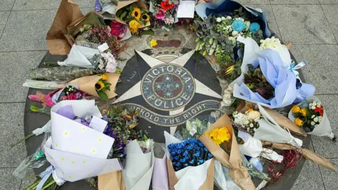 Getty Images Floral tributes laid on the ground on a Victoria Police emblem
