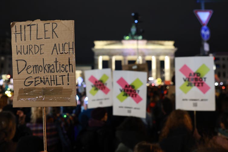 A protest sign that reads 'Hitler was also democratically elected' in German.