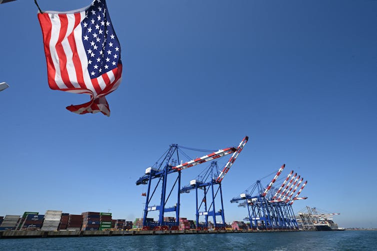 A US flag seen flying with the port of Los Angeles in the background