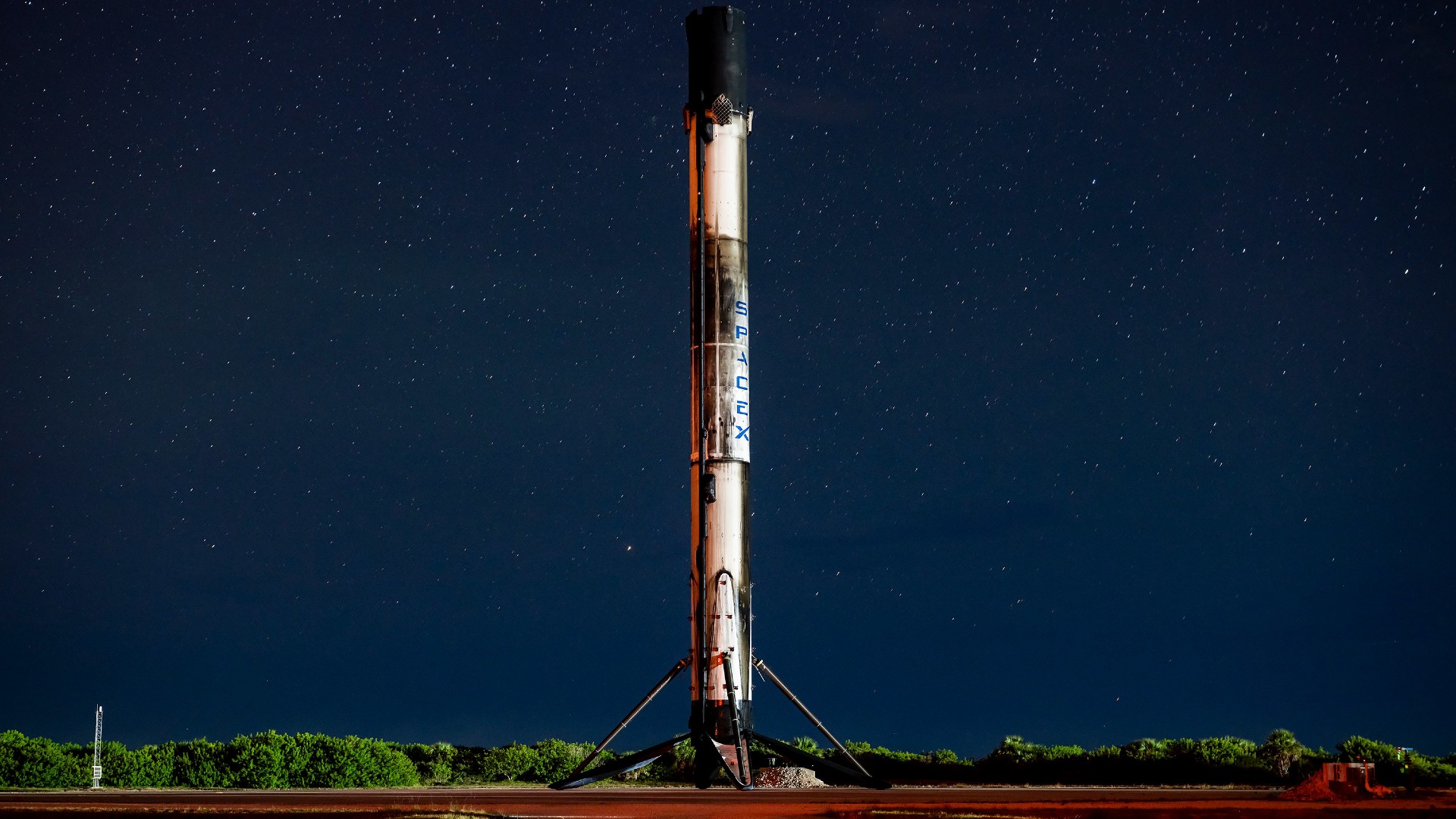 a white rocket lifts off above a plume of fire