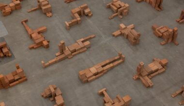 a detail of a room-size art installation by Antony Gormley of blocky terracotta forms resembling human figures in various positions