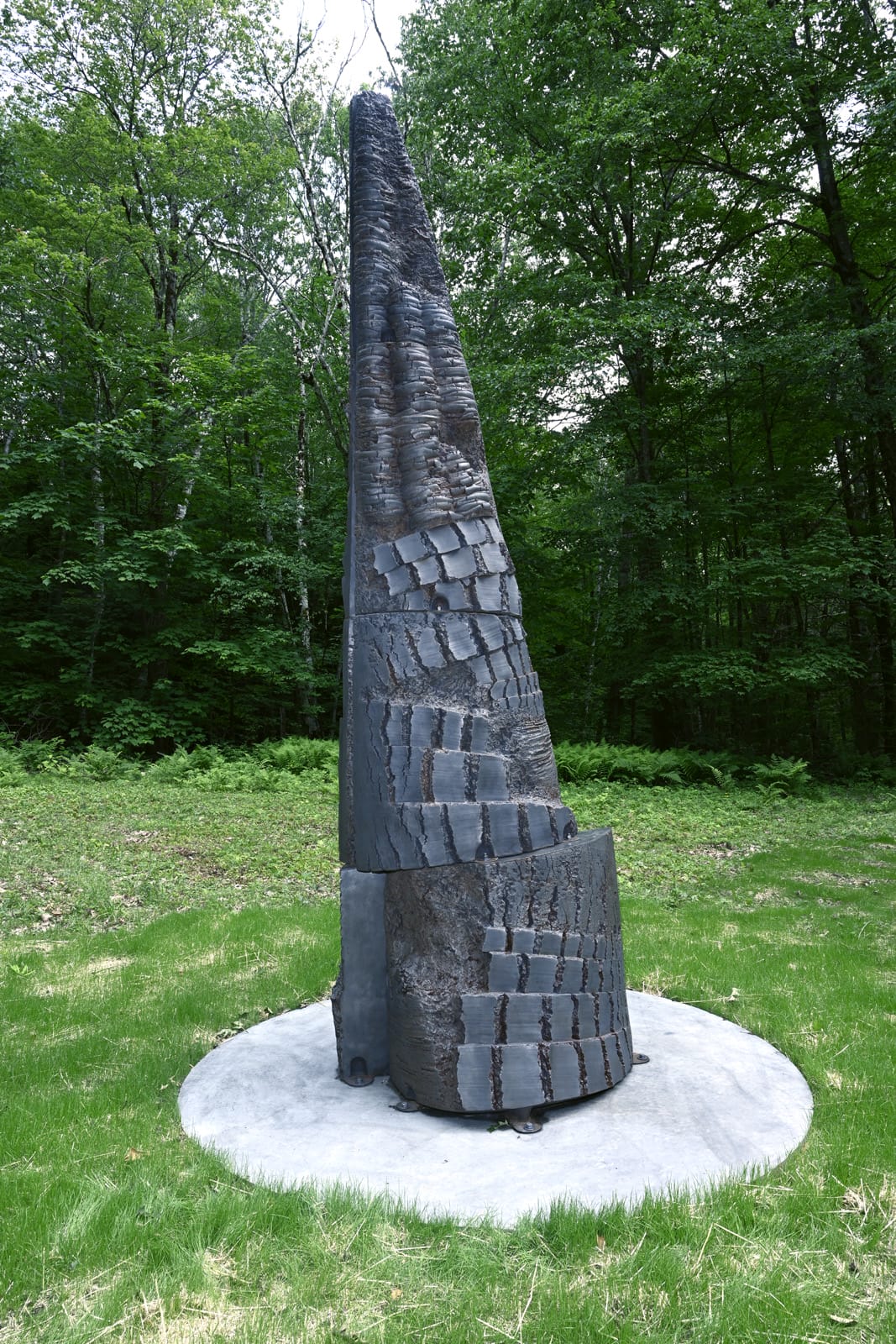 a conical, black, abstract sculpture by Yō Akiyama installed outdoors