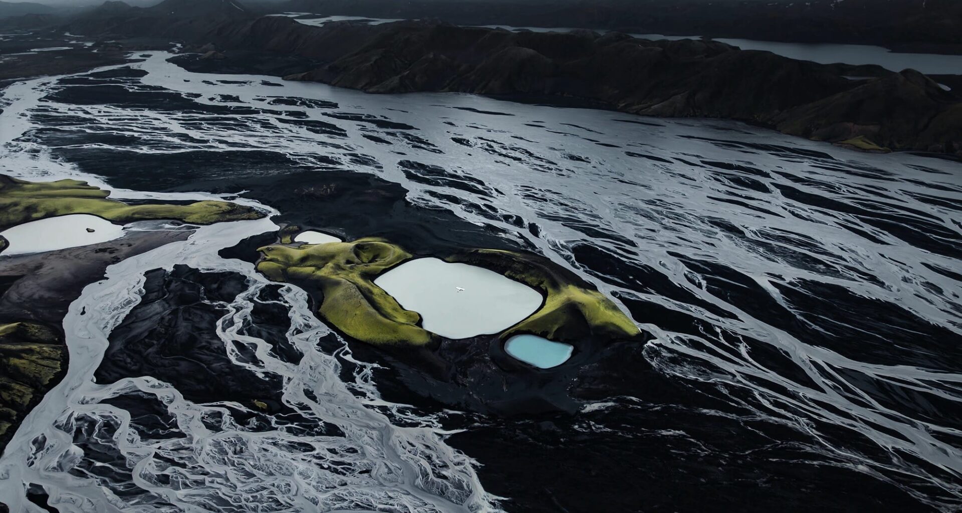 a dramatic Iceland landscape photographed from the air by Dani Guindo showing rivers, a glacial lake, and a tiny plane