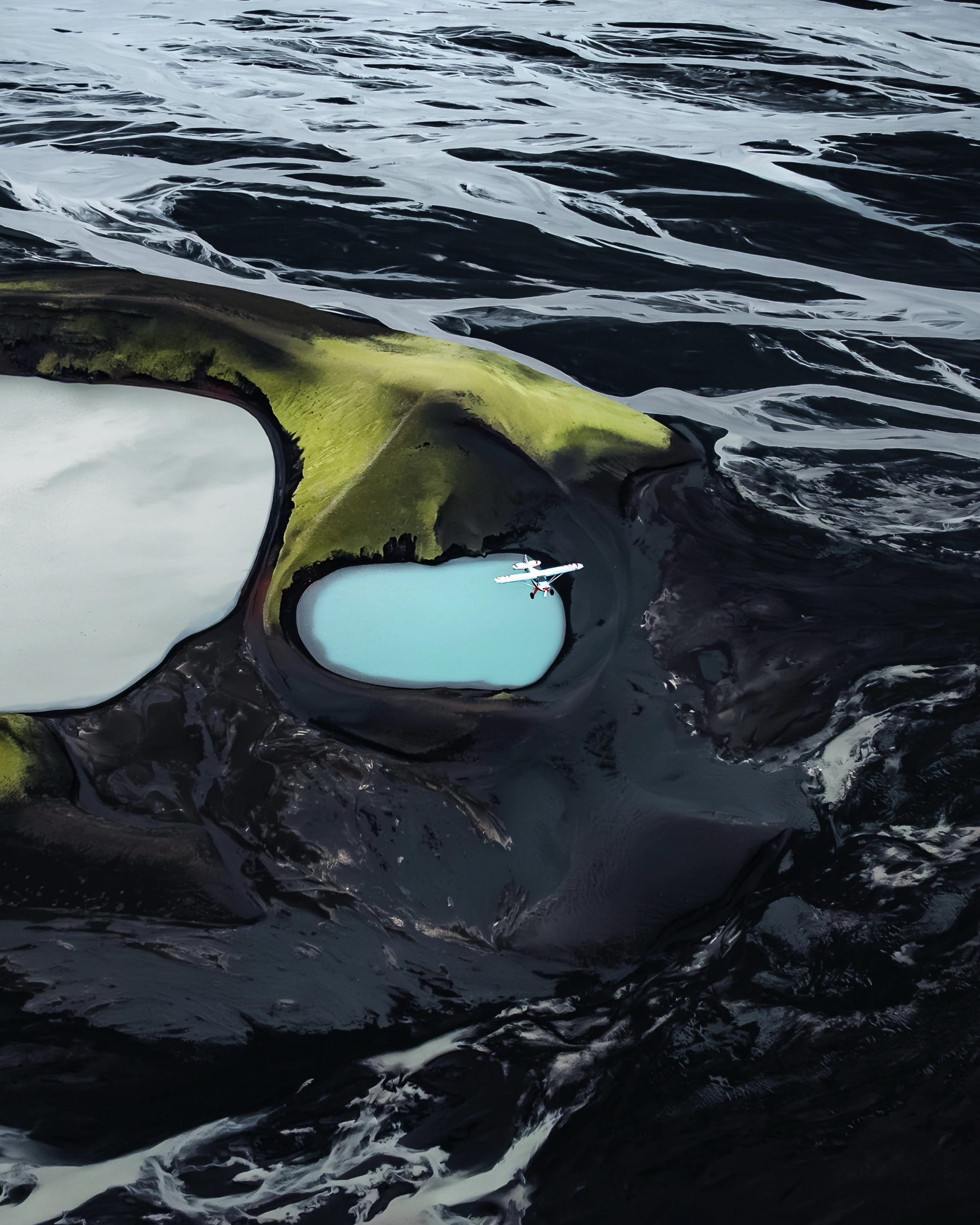 a dramatic Iceland landscape photographed from the air by Dani Guindo showing rivers, a glacial lake, and a tiny plane