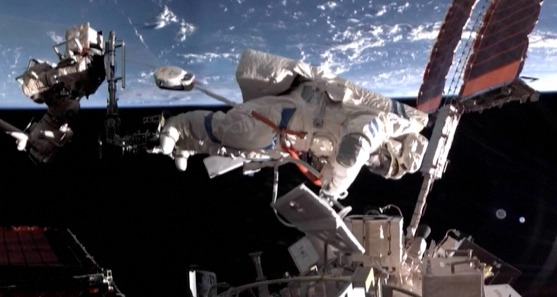 an astronaut in a white spacesuit works outside a space station with earth in the background