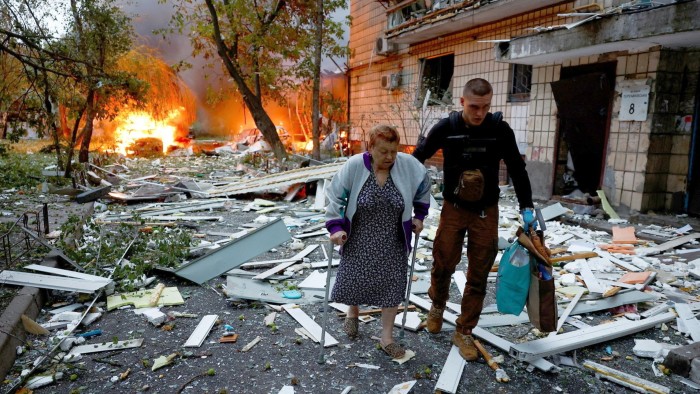 A woman receives assistance as she leaves the apartment building hit during Russian missile and drone strikes in Kyiv