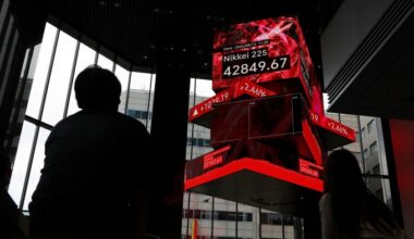 People watch a large electronic display showing the Nikkei 225 index at 42,849.67 points