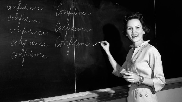 A female teacher uses a blackboard in a classroom