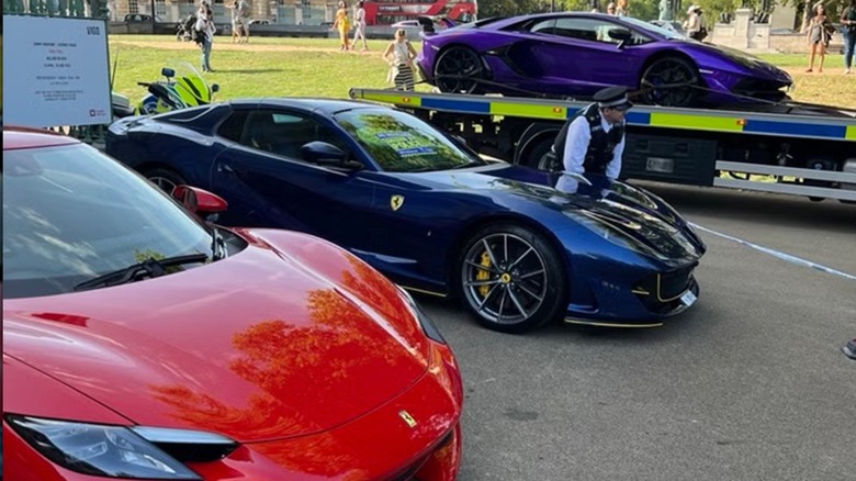 several supercars parked outside being towed by police