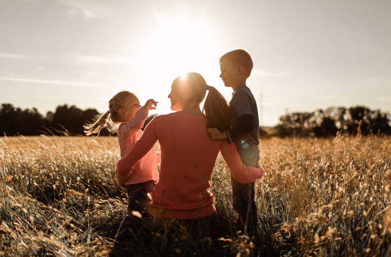 Mother and two children in a field at sun set