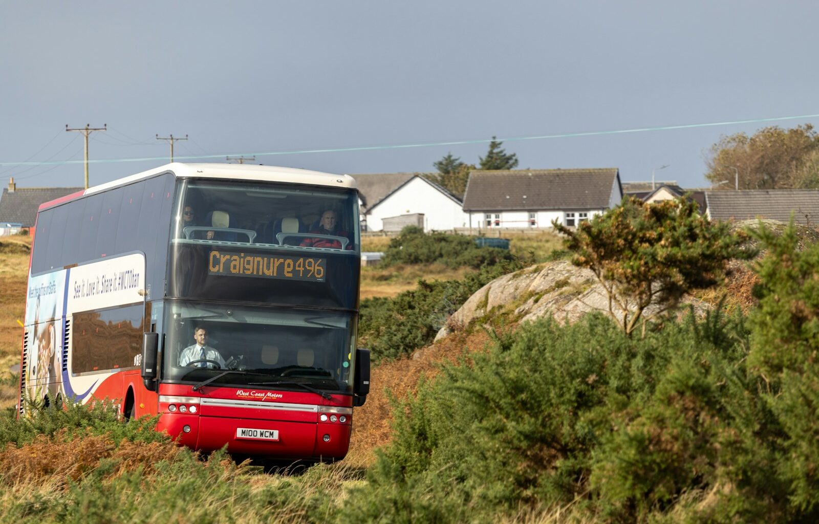a double decker bus driving down a dirt road