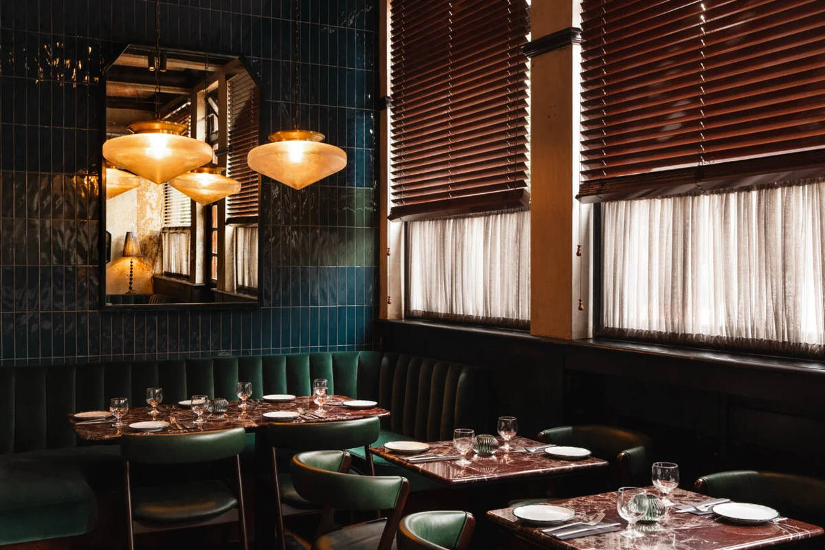 the warm green and brown hued interiors of cosy restaurant kudu grill, with banquette seating along the walls