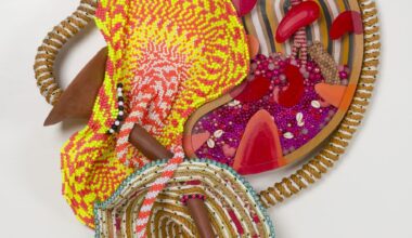 an abstract yellow and magenta sculpture by Maria Nepomuceno made of beads, resin, wood, and string