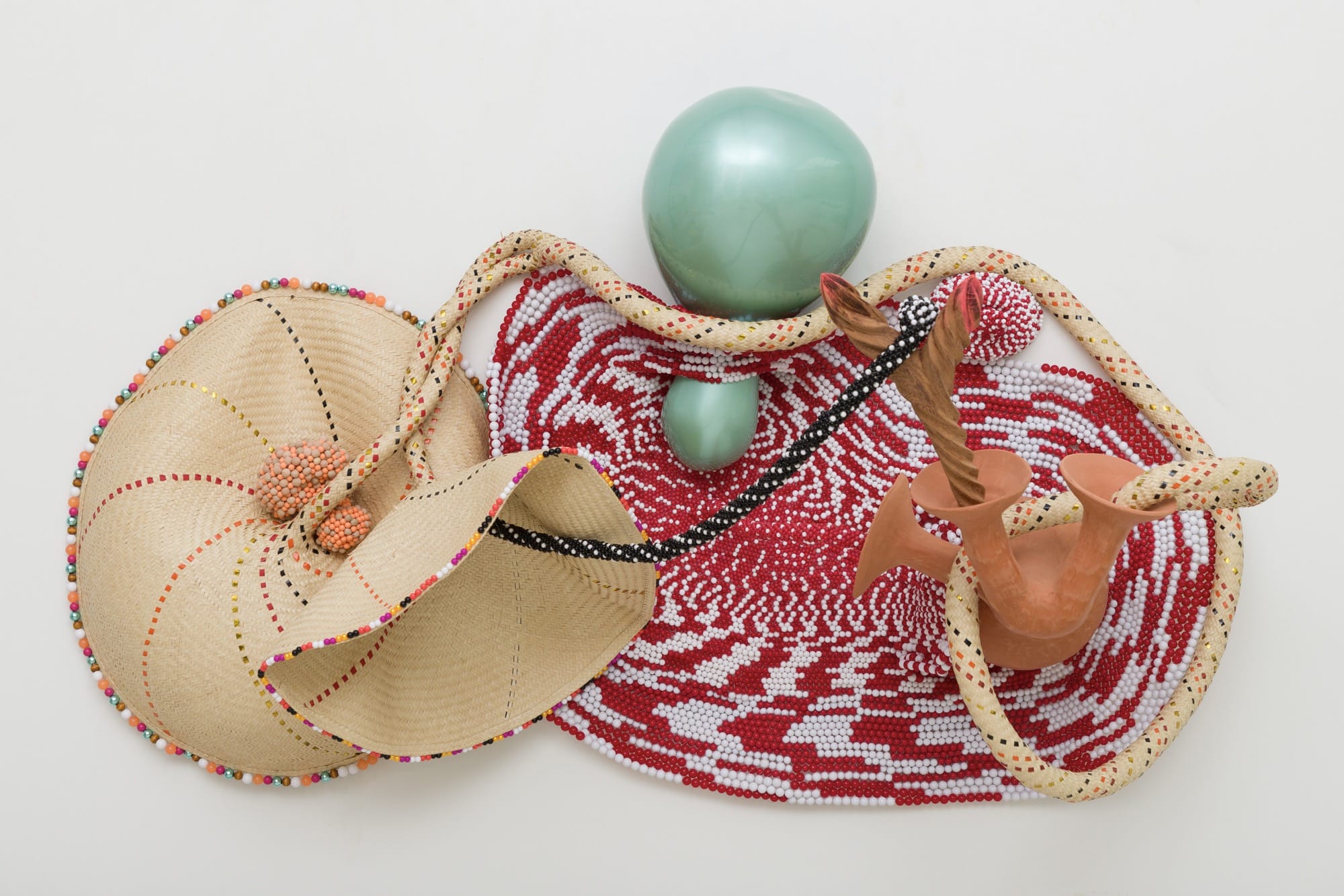 an abstract wall sculpture by Maria Nepomuceno made of beads, resin, wood, and string