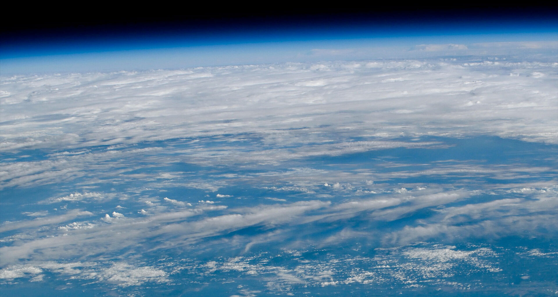 a view of Earth as seen from orbit with blue waters and white clouds set against the blackness of space