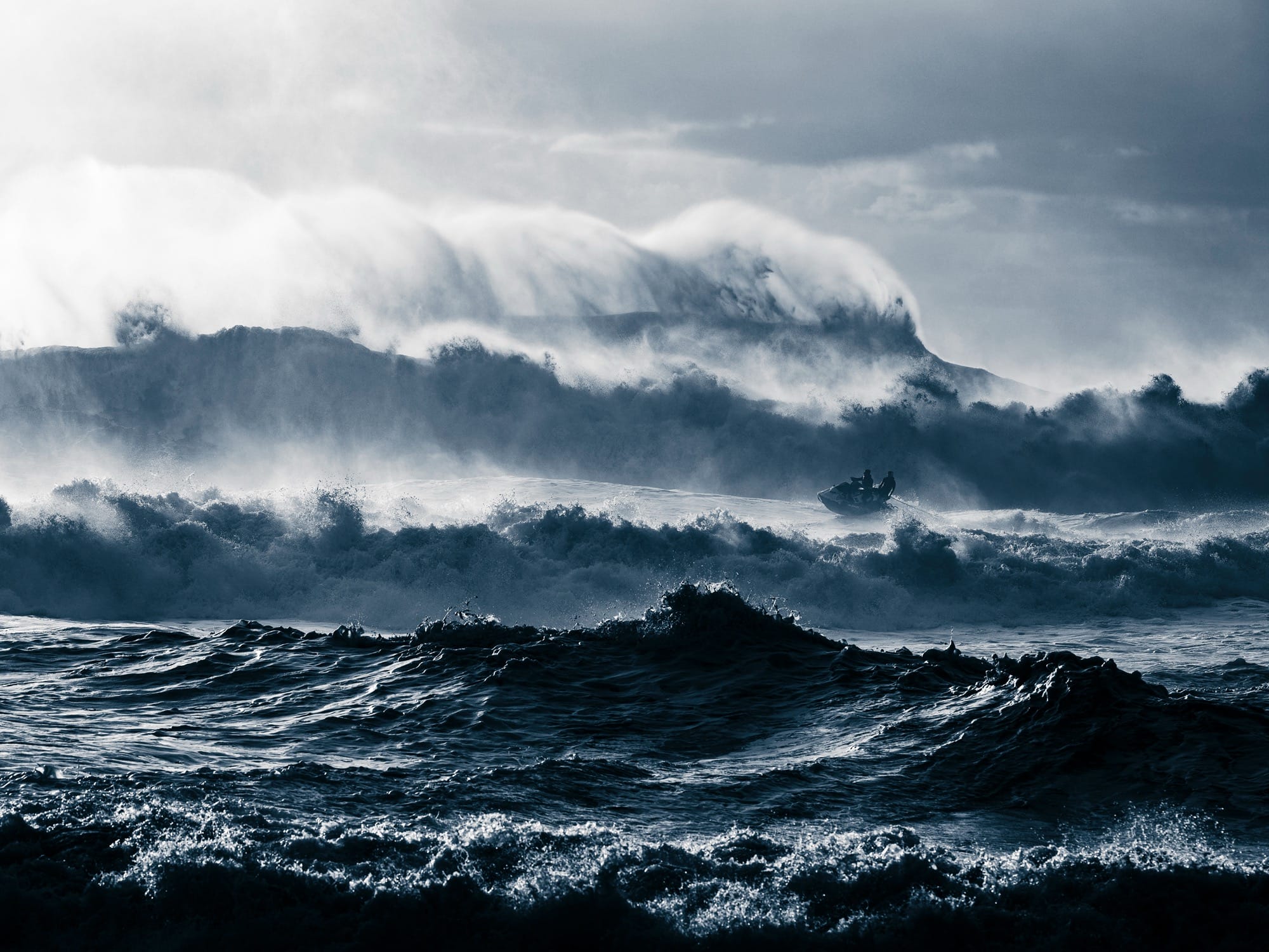 a small watercraft rides wild waves near Nazaré, Portugal