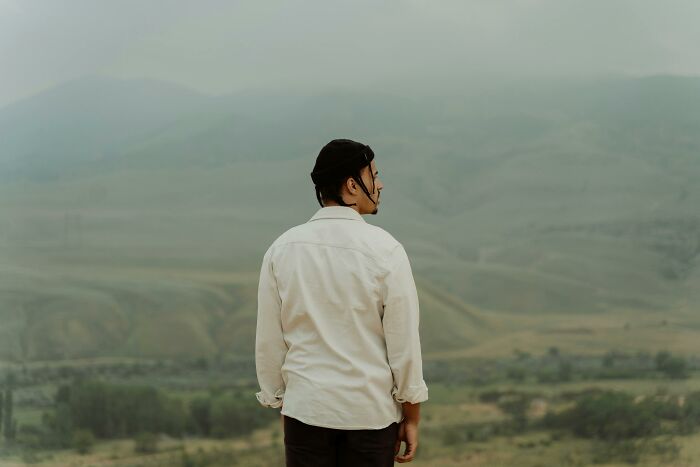Person in white shirt and black beanie looking at a vast natural landscape, symbolizing cool facts about the human body.