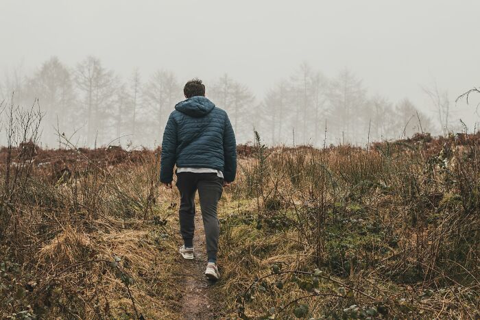 Person walking on a nature trail wearing a blue jacket, illustrating cool facts about the human body and fascination with it.