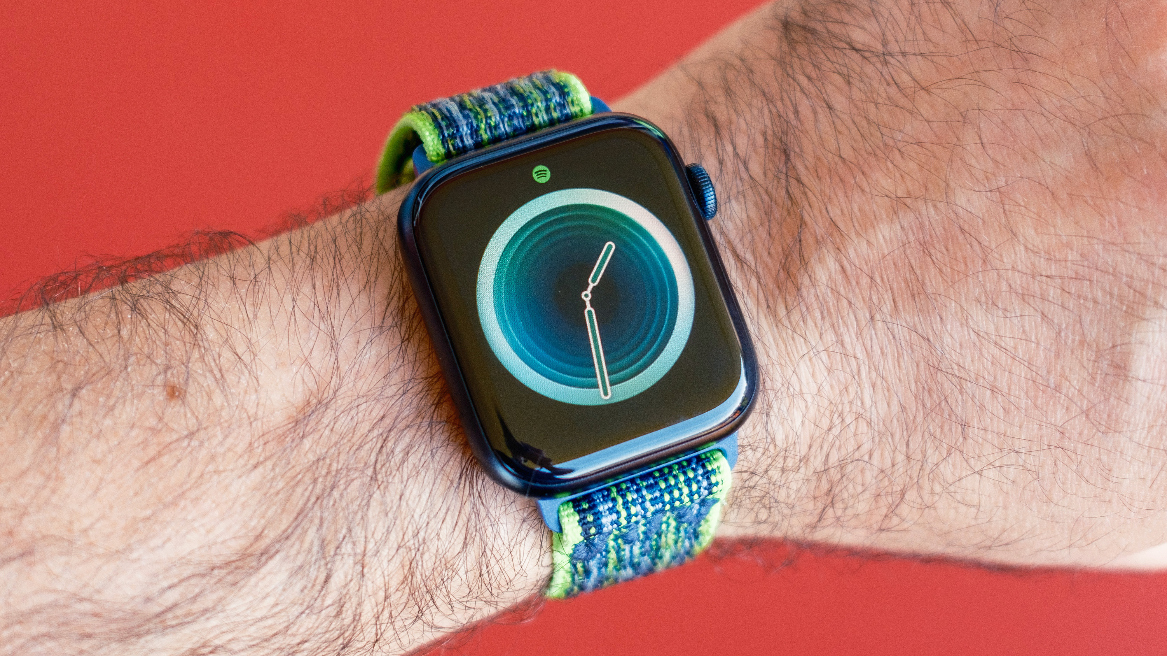 Apple Watch SE 2nd generation on a user's wrist against a red background