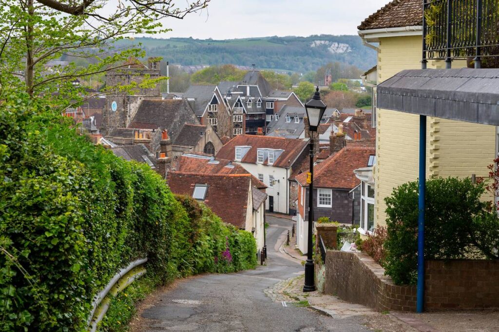 Scenic old street with a streetlamp in the foreground and a church in the background winding downhill in the town of Lewes