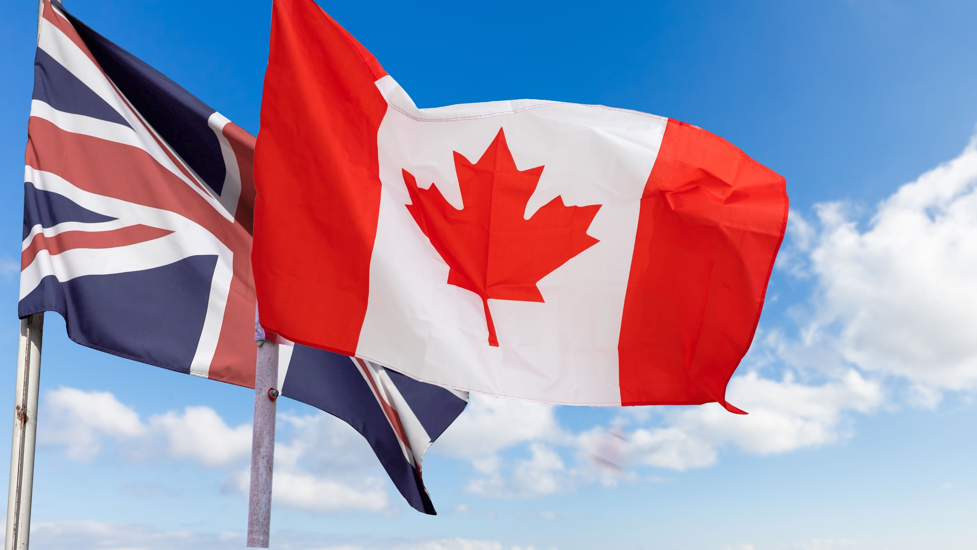 Canadian and British flags against the background of the blue sky