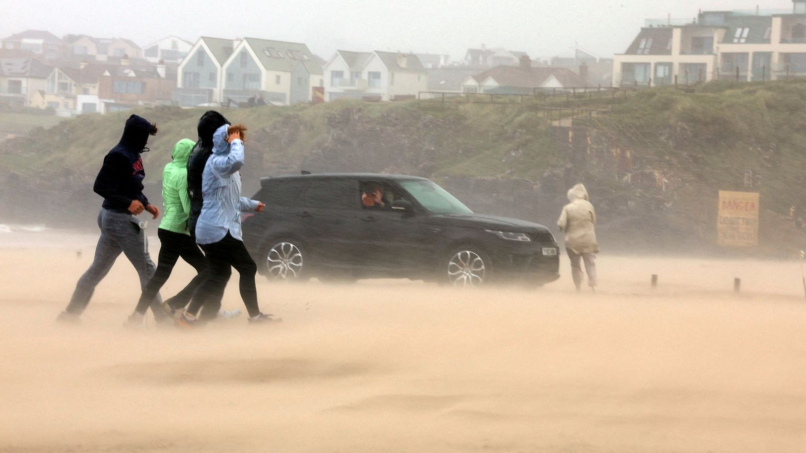 People run for cover as Storm Floris hits the north coast of Northern Ireland. Pic: Reuters