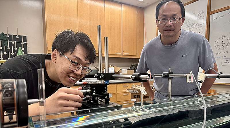 Zhengwu Wang (left) a doctoral student studying physics, adjusts his camera to best capture the movement of water through a barrier in microgravity-like conditions. Wang and Likun Zhang, senior scientist at the National Center for Physical Acoustics, recently published research on manipulating the flow of water through barriers in Physical Review Letters. Credit: Clara Turnage/University Marketing and Communications Tiny waves, big impact: Study finds new way to control fluid in space