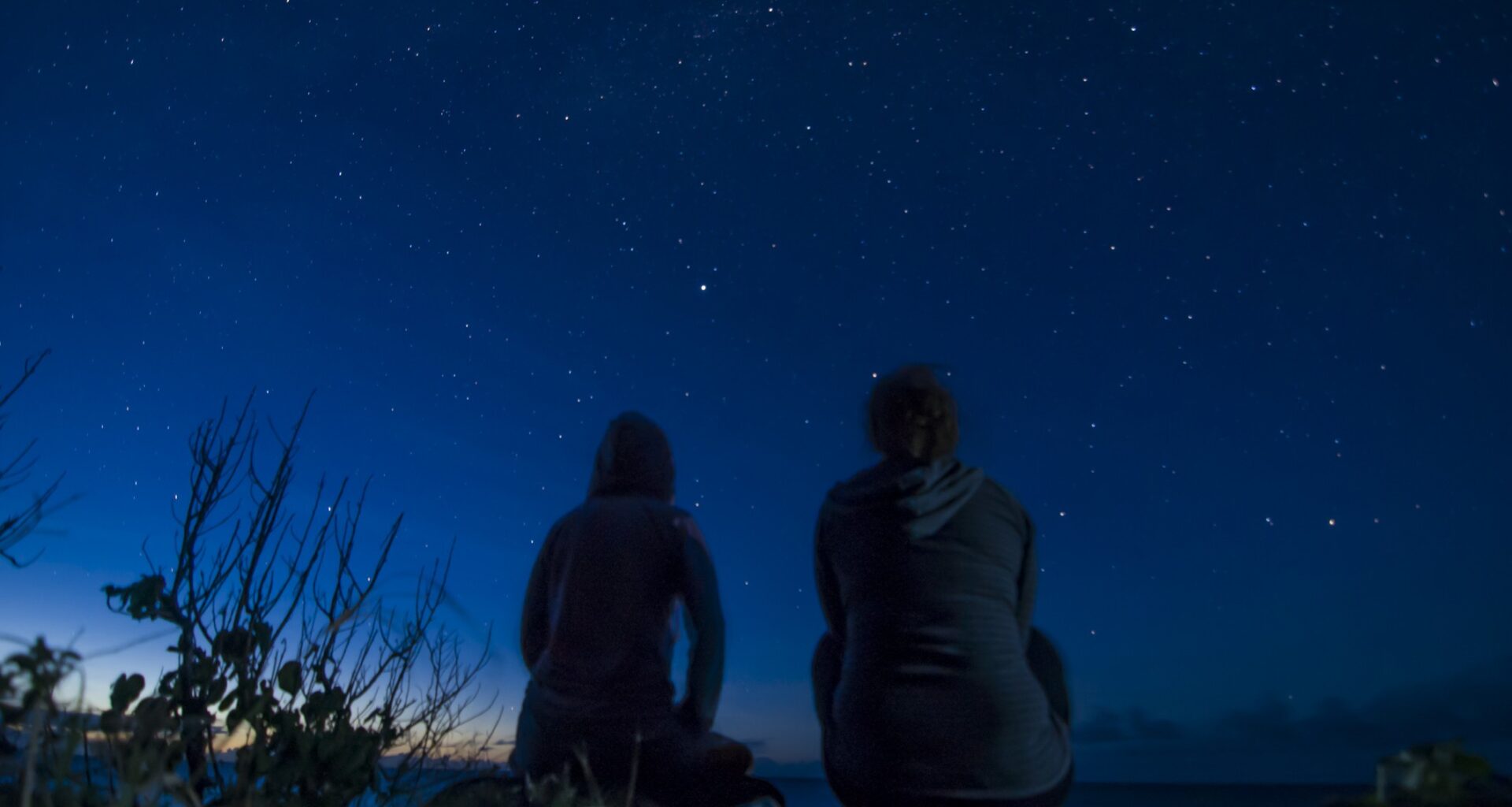 Two people sit and look at a moonless sky.