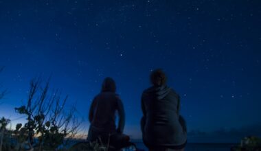 Two people sit and look at a moonless sky.