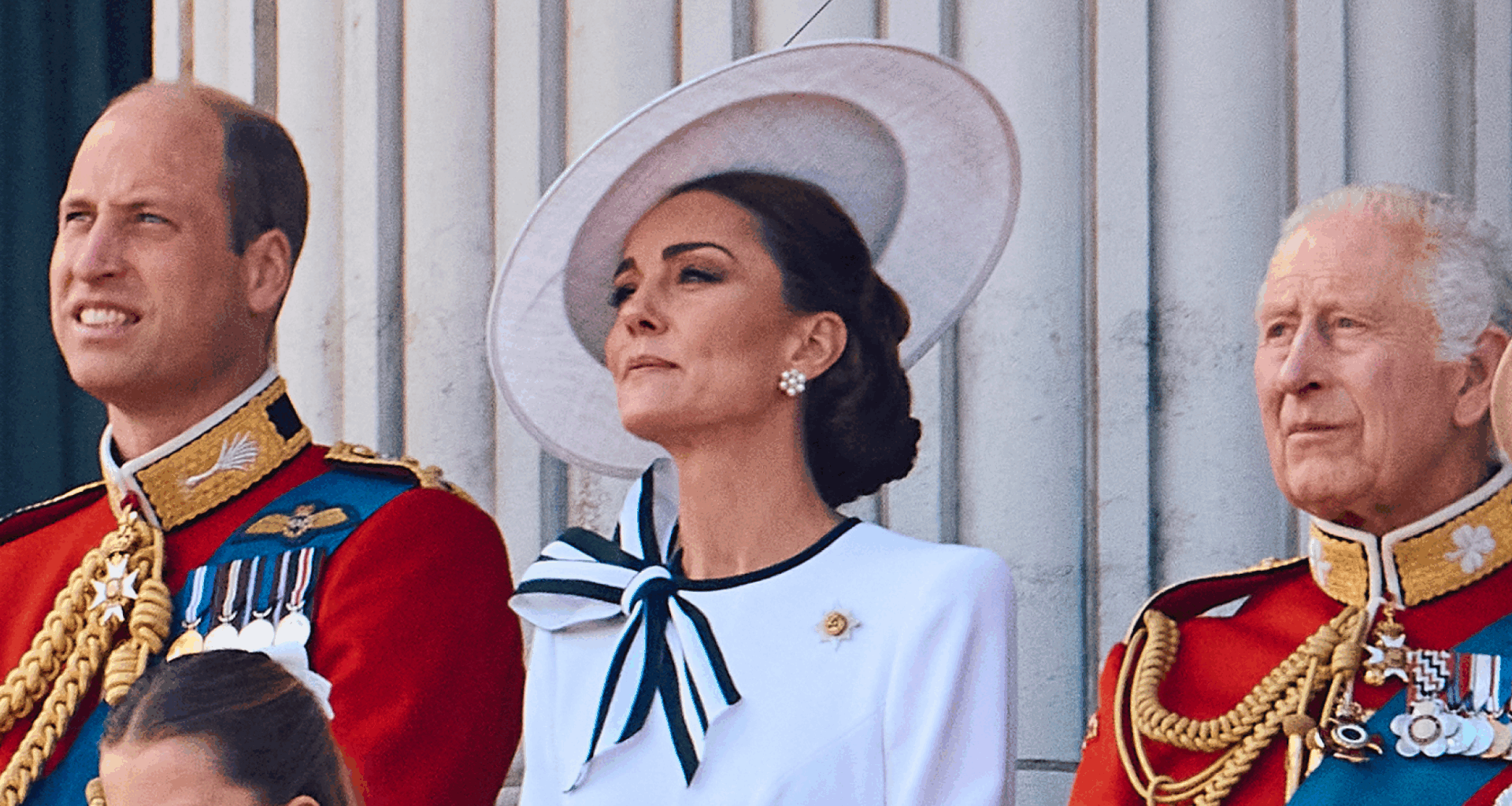 Prince William and King Charles wear military uniform as they stand on the Buckingham Palace balcony with Kate Middleton, who wears a white dress with navy accents
