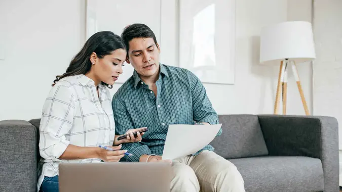 Couple sitting on a couch and looking at bank statements.