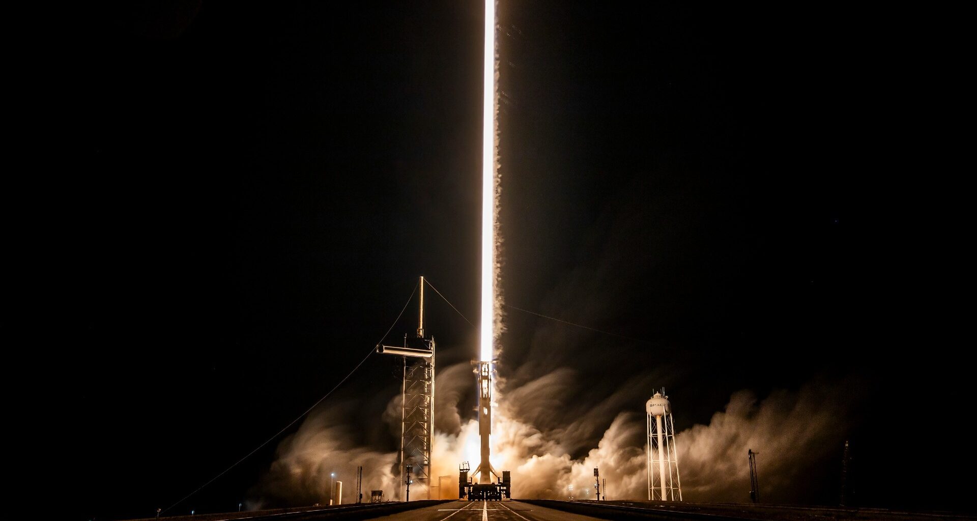 a white rocket lifts off above a plume of fire