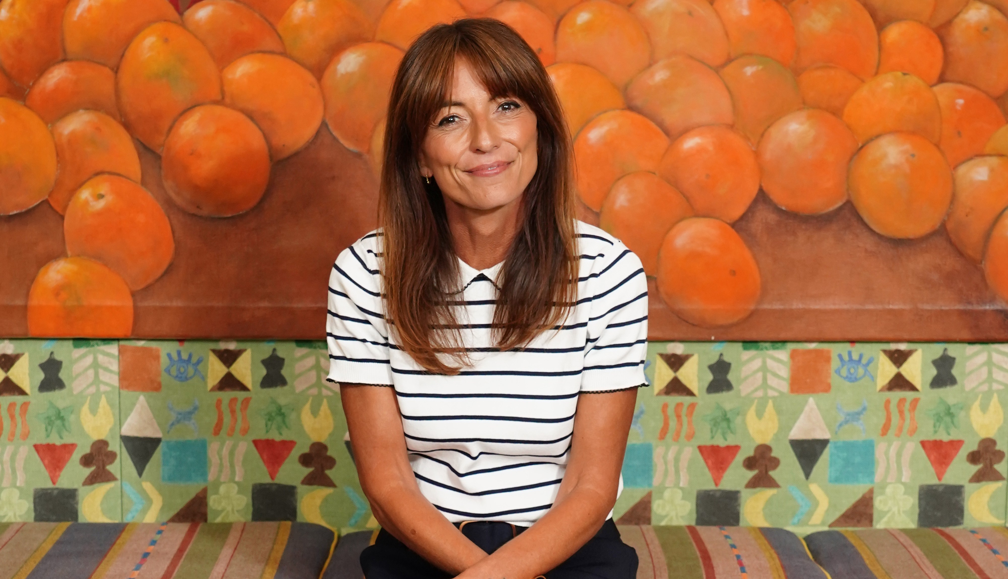 Photo of Davina McCall sitting on a patterned bench.