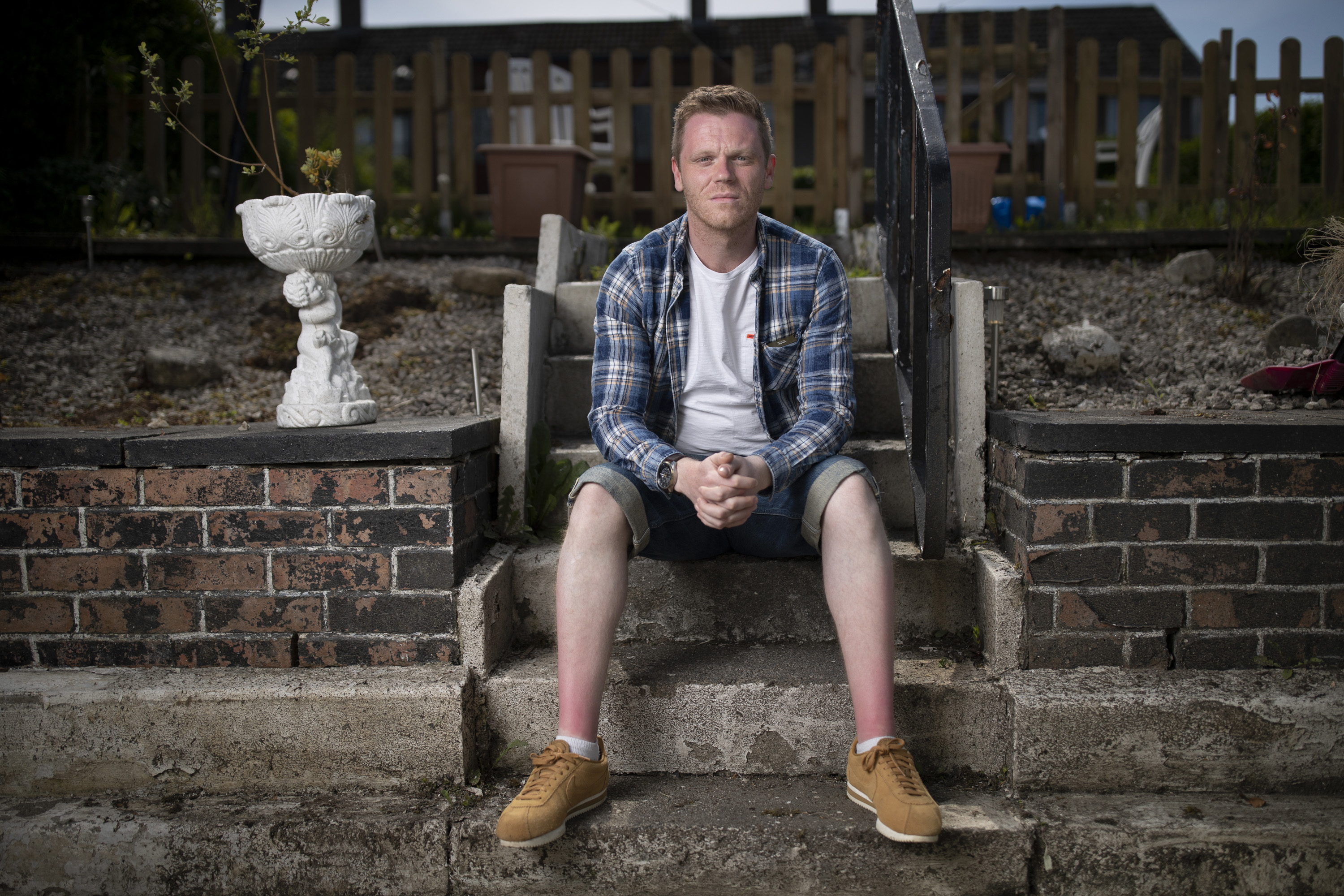 Portrait of Darren Mcgarvey (AKA Loki) sitting on steps outside his home.