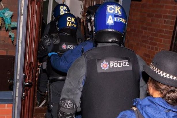 Operation Vulcan officers storm a home in Derker, Oldham, today.