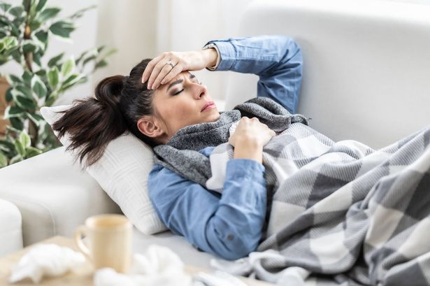 A very sick young woman lying on a couch fighting a fever.