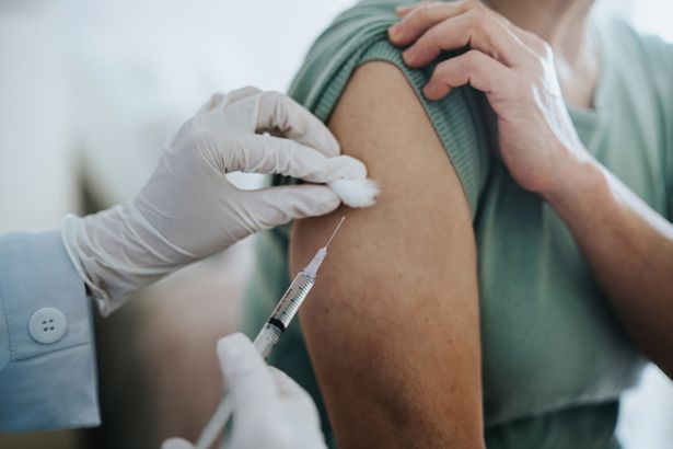 Close up of senior Asian woman getting Covid-19 vaccine in arm for Coronavirus immunization by a doctor at hospital.